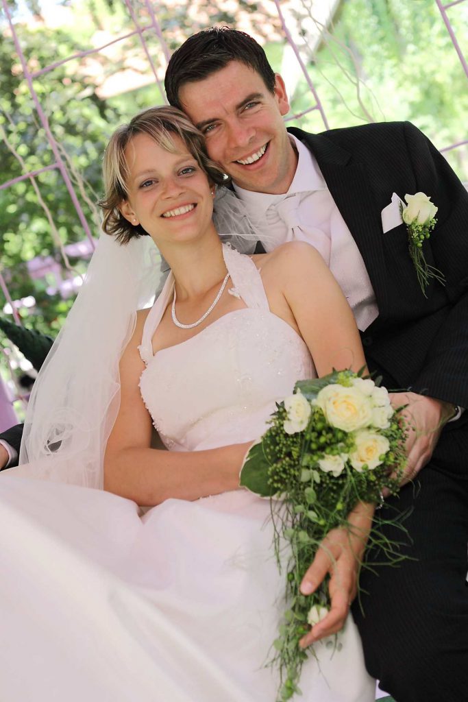 Elegante Hochzeit in Halle - Brautpaar lächelt sitzend in Kamera