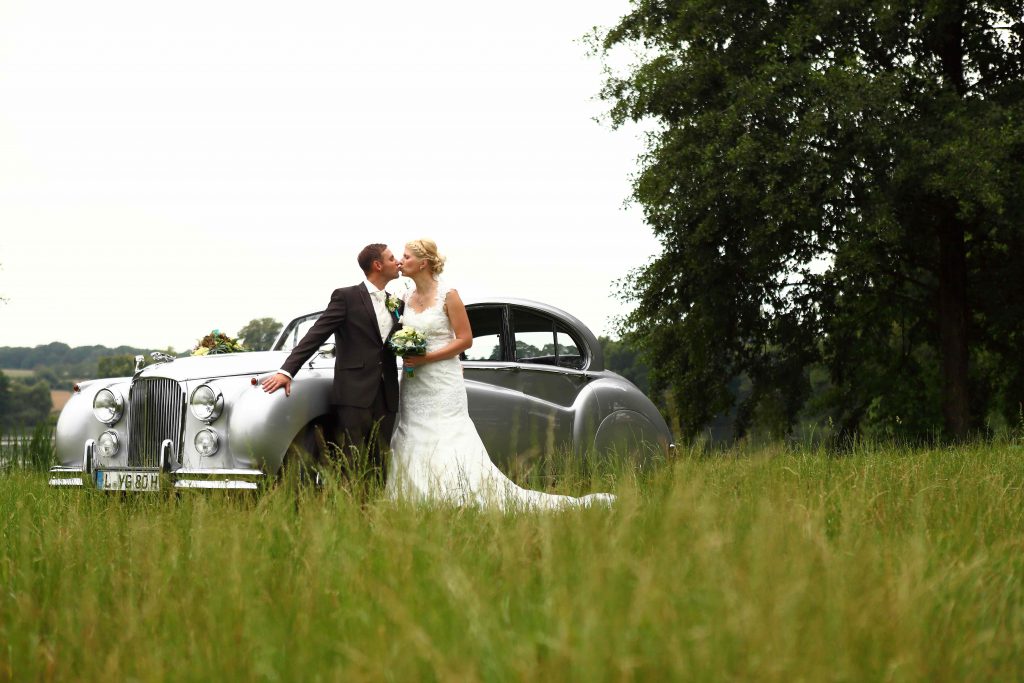 Brautpaar vor Hochzeitsauto