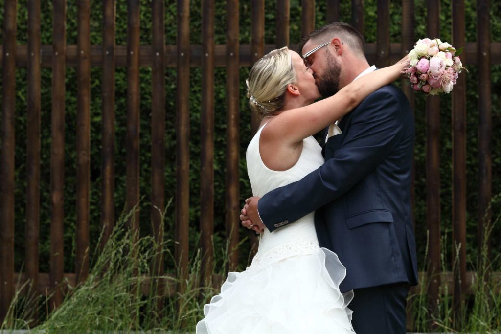 Hochzeitspaar vor Zaun