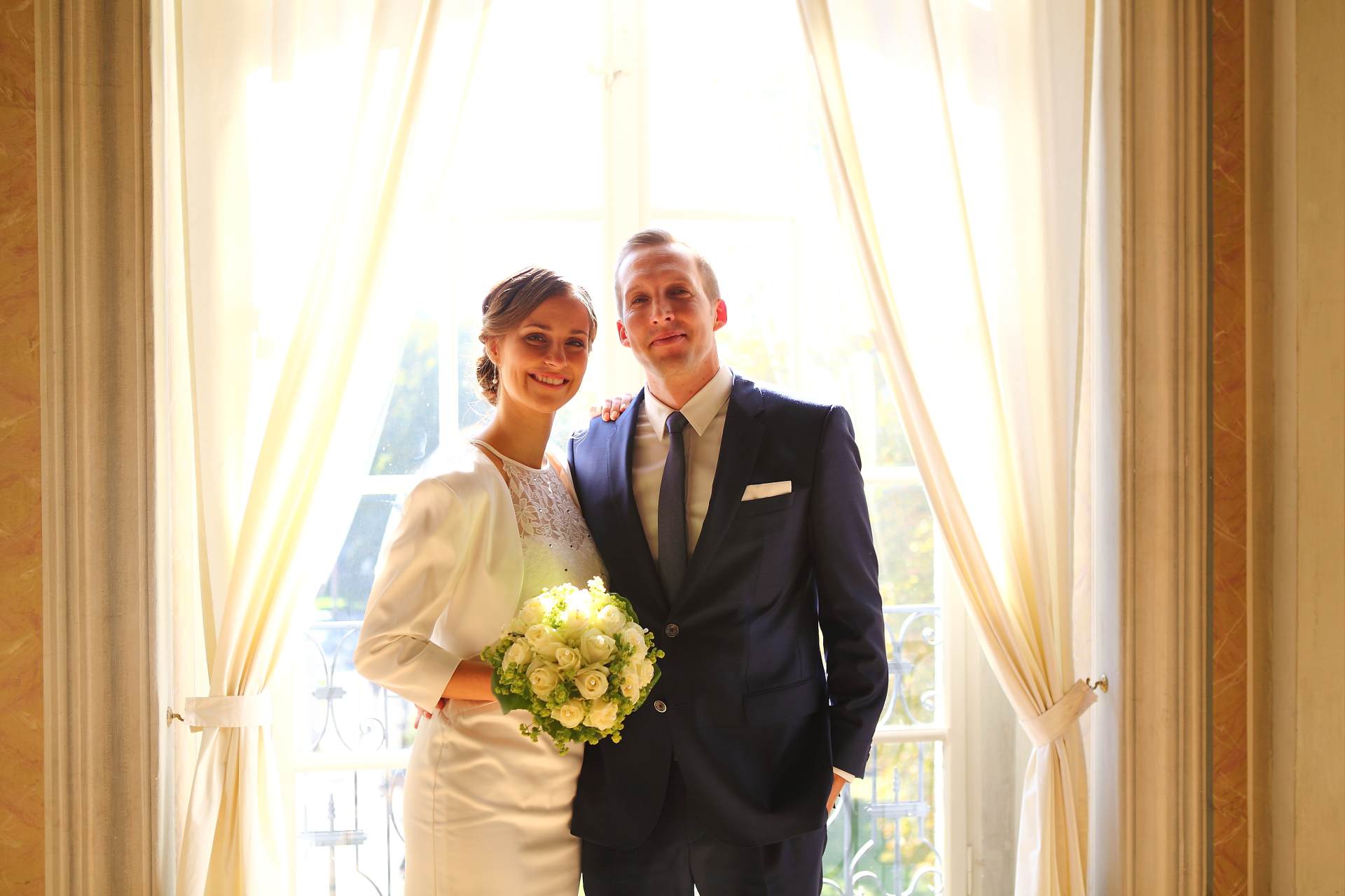 Hochzeitsfotos in Leipzig - Hochzeitspaar mit Brautstrauß vor dem Fenster