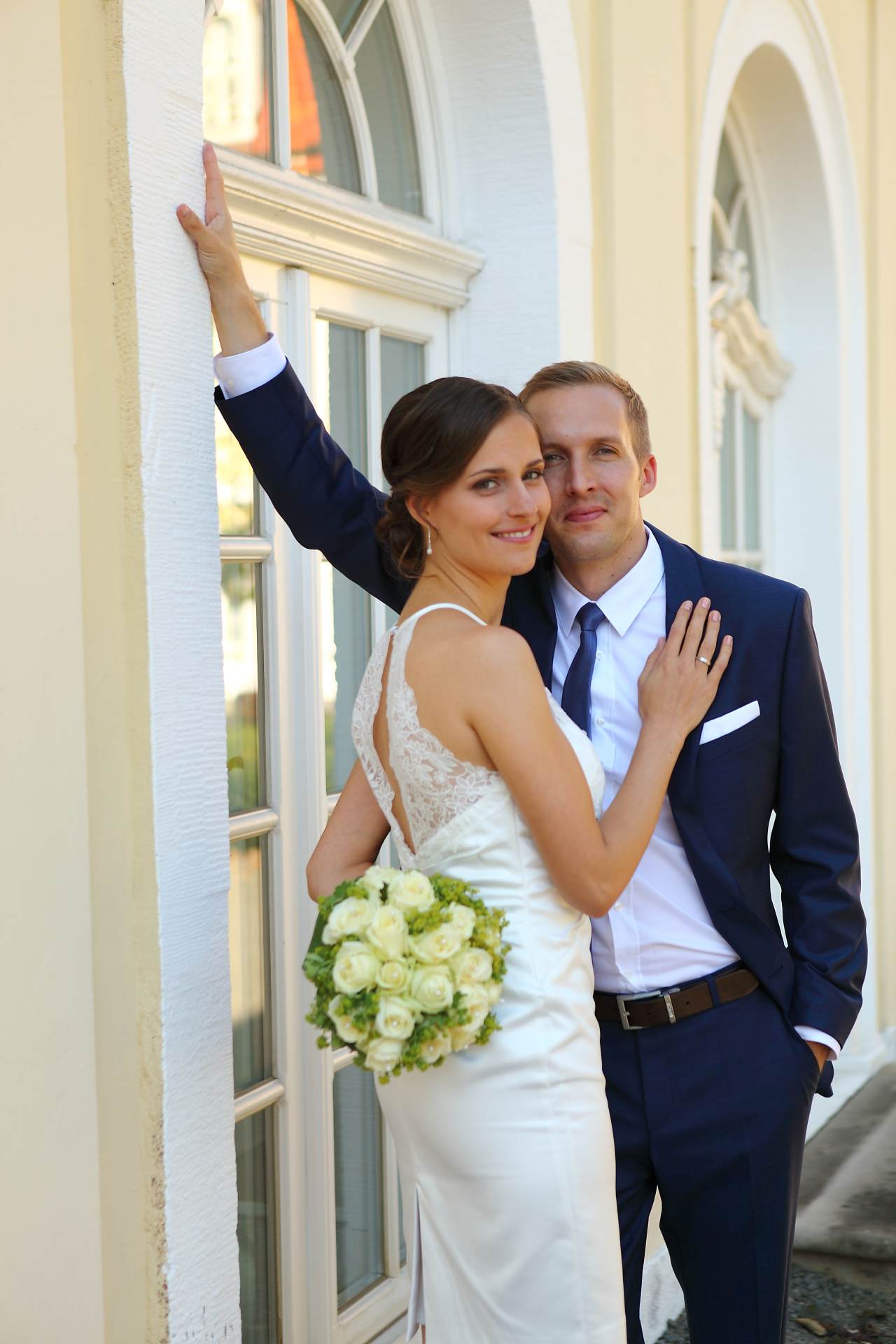Hochzeitsfotos in Leipzig - Hochzeitspaar lehnt an der Mauer und schaut in Kamera