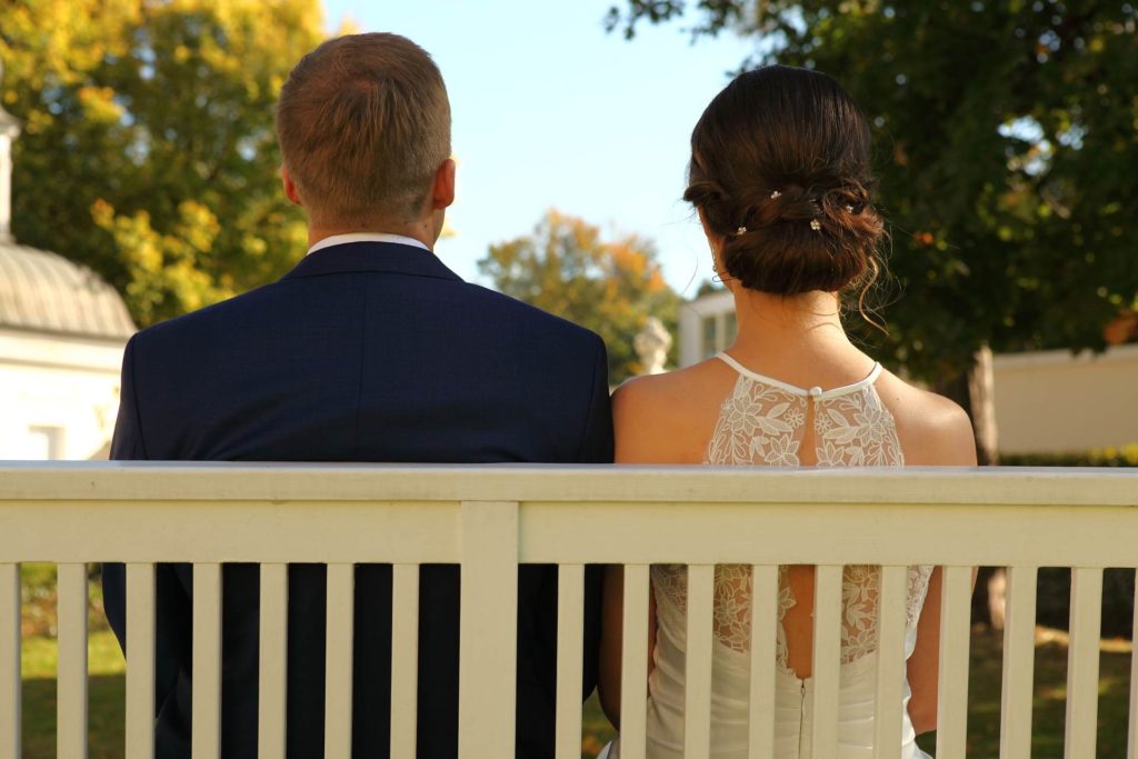 Hochzeitspaar von hinten auf einer Bank